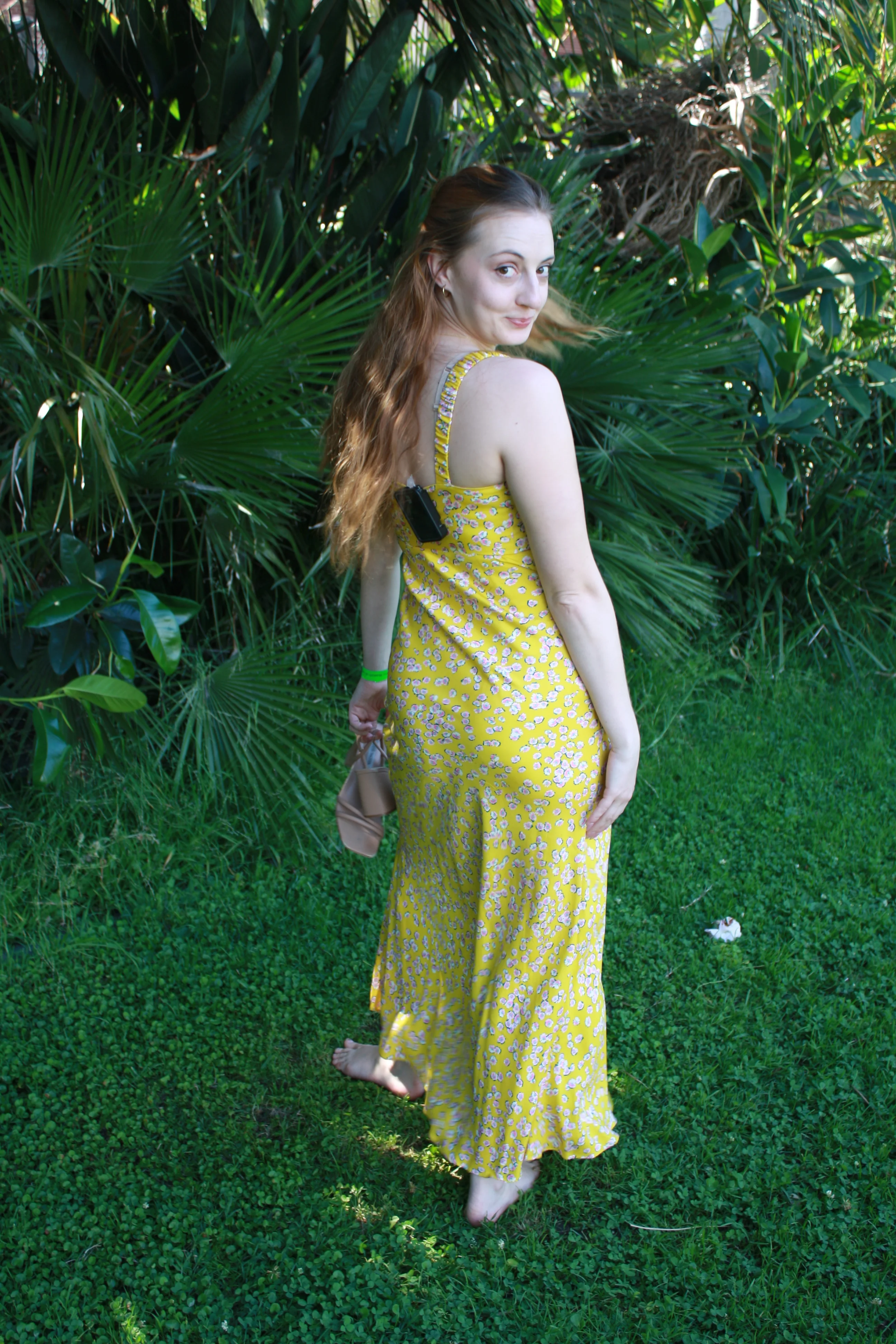 Jordie Morris looking back in a yellow dress beside palm fronds at the Exposition Park Rose Garden.